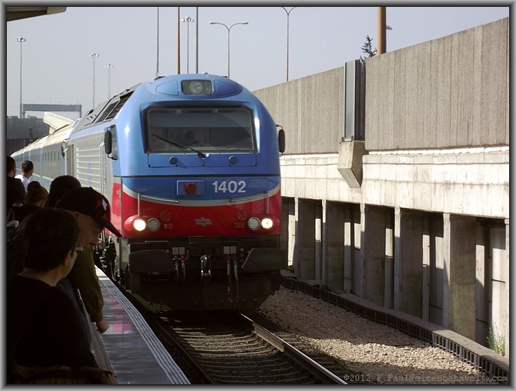 Die erst im Jahr 2011 in Spanien gebaute Vossloh-Lok Nr.1402 erreicht am Mittag des 25.04.2012 mit dem Schnellzug Nr.148 aus Modi'in den Bahnhof Tel Aviv-HaHagana. Der Zug durchquert Israel und wird erst in Naharyya an der Grenze zum Libanon enden.